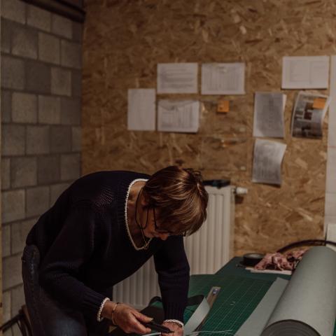 Vrijwilliger snijdt zuurvrij papier op maat om de archiefstukken te beschermen.