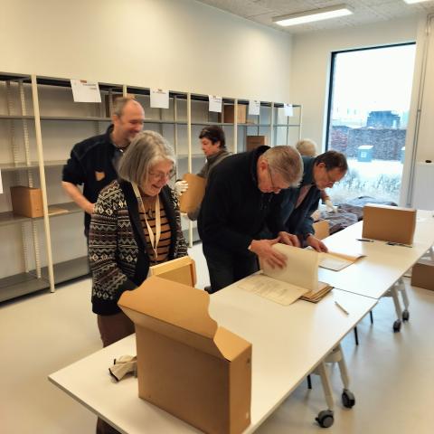 Groep erfgoedvrijwilligers buigt zich over archiefstukken uit de gemeentearchieven