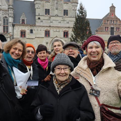 Groep van negen erfgoedvrijwilligers poseert samen met de coördinator van Erfgoedcel Mechelen voor de foto tijdens de nieuwjaarsreceptie van Stad Mechelen